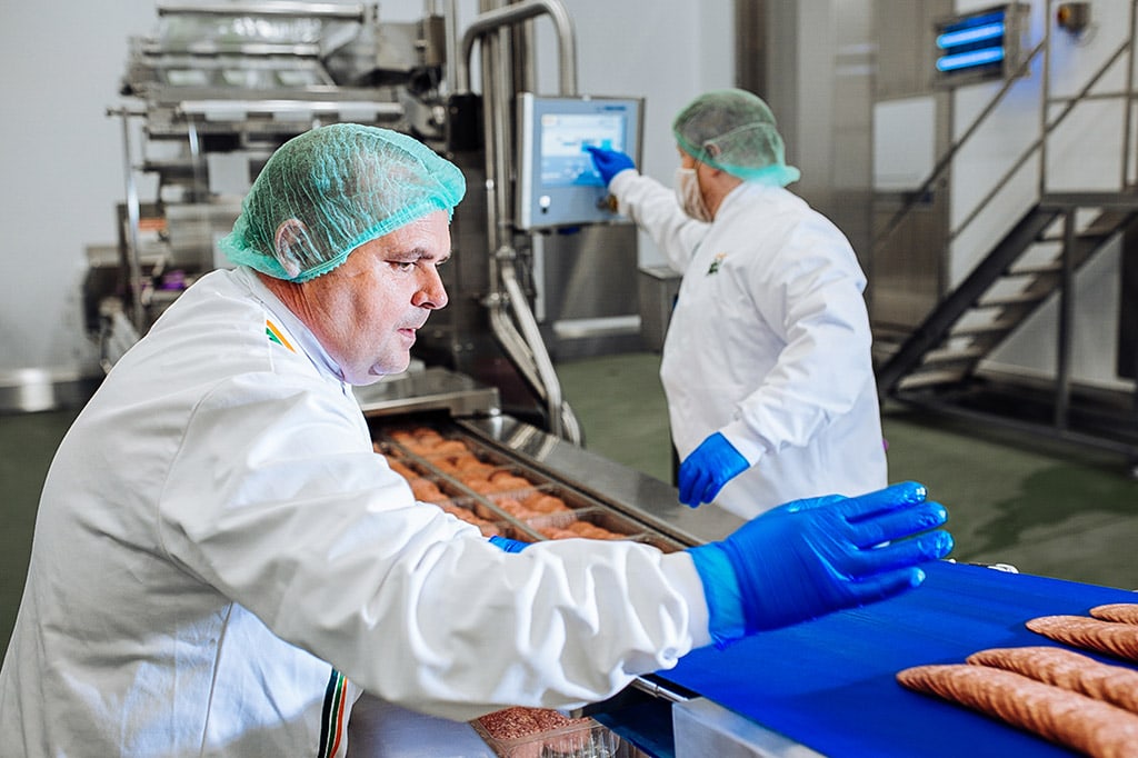 Two men in white coats and hairnets work at a production line in the Dawn Farms state-of-the-art facilities.