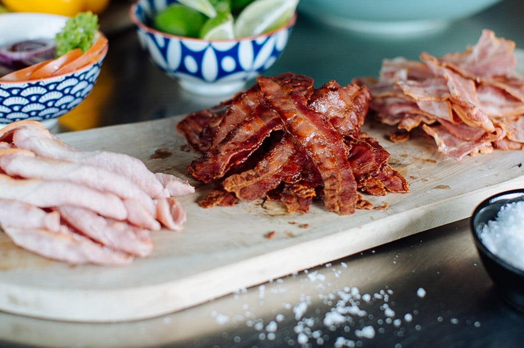 An array of Dawn Farms bacon ingredients on a wooden platter showing different levels of cooking, from crispy to soft and juicy.