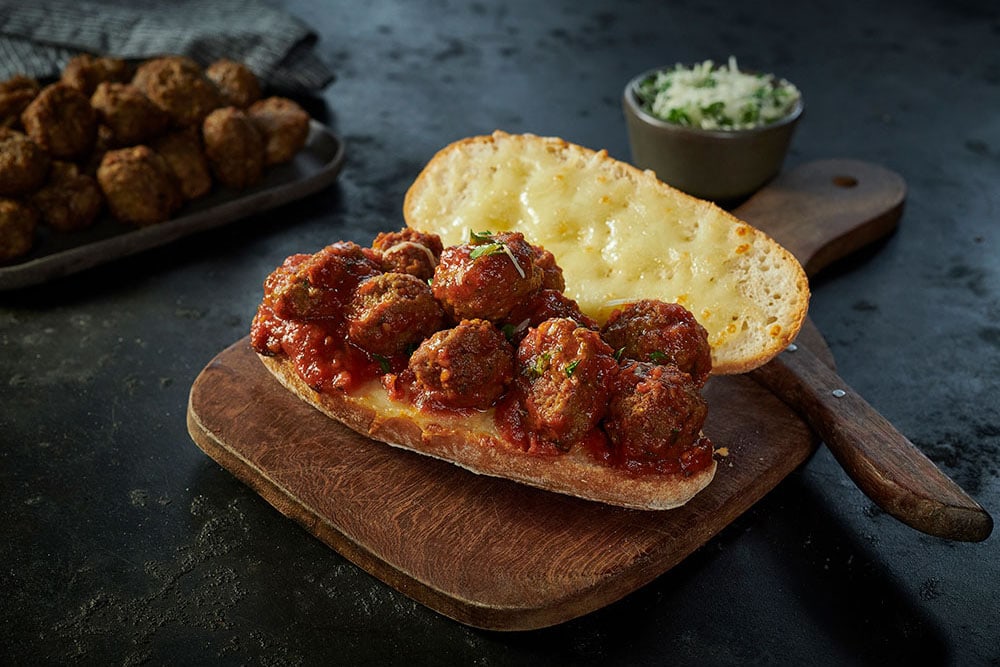 A toasted sub roll with delicious Dawn Farms Batch 85 chunky meatballs in tomato sauce on a base of melted cheese.