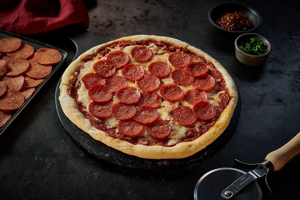 A cheese and tomato pizza with Dawn Farms Batch 85 sliced pepperoni topping.